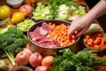 hand adding thick cut vegetables into beef stew