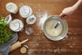 Hand adds ingeredients with spoon into bowl flour dough