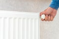 Hand adjusting the knob of heating radiator at home a cold season.