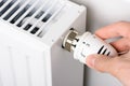 Hand adjusting the valve knob of heating radiator temperature thermostat in winter Royalty Free Stock Photo