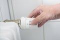 Hand adjusts the thermostat on the heater, the energy crisis with rising prices forces to reduce the heat, copy space, selected