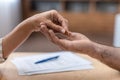 Hand of adult caucasian female gives ring to her ex husband at table with divorce papers, close up, cropped