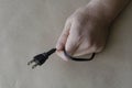 Hand of an adult Caucasian male is holding black electric plug. DC power plug Royalty Free Stock Photo