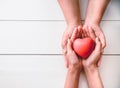 The hand of an adult holding a child`s hand with a red heart in Royalty Free Stock Photo