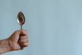 Hand of an adult male holds a metal spoon