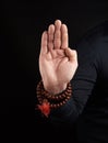 Hand of an adult male shows abhayaprada mudra on a dark background, protective gesture