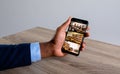 Hand of african american man holding smartphone with view of library from security cameras on screen