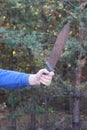 the hand of an aggressive man in blue clothes holds a large old rusty brown machete knife