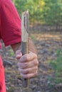 the hand of an aggressive man in a red shirt holds a piece of a gray wooden stick