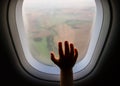 Hand on an airplane window with landscape in the the blurred background