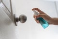 Hand applying alcohol spray on door, doorknob for protect coronavirus or covid-19, germs, virus, and cleaning Royalty Free Stock Photo