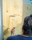 Hand applying clear coat paint on a wooden surface with roller brush. Painting wood wall and floor Royalty Free Stock Photo