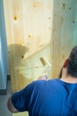 Hand applying clear coat paint on a wooden surface with roller brush. Painting wood wall and floor Royalty Free Stock Photo