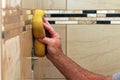 Hand applying grout to wall tiles