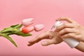 Hand applying natural lotion skincare, Cosmetic bottle containers packaging with tulip flower essence