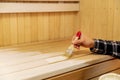 Hand applying wood protective wax on sauna bench