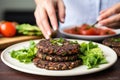 hand arranging black bean burgers on a plate