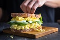 hand arranging egg salad over a crispy roll