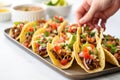 hand arranging mini-tacos on a serving platter