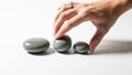 Arranging three smooth, gray pebbles of different sizes on a white Royalty Free Stock Photo
