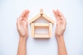 Hand arranging wood block as house.