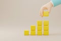 Hand arranging yellow block stacking as step stair on background
