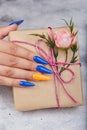 Hand with artificial manicured nails colored with blue and orange nail polish Royalty Free Stock Photo