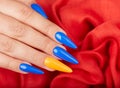 Hand with artificial manicured nails colored with blue and orange nail polish Royalty Free Stock Photo