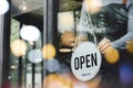 Hand of asain staff woman wearing apron turning open sign board on glass door in modern cafe coffee shop, hotel service, cafe rest Royalty Free Stock Photo