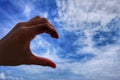 Hand of Asia women and making heart with her hand on blue sky.