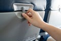 Hand of asian female passenger try to open a tray in front of the seat in low cost airplane by slide to unlock and ready for infli