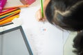 Hand of Asian little girl is writing or drawing with pencil on blank paper sheets on the table at school .selective focus Royalty Free Stock Photo