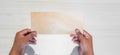 Hand of an Asian man holds blank envelop against white background