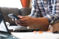 Hand of asian people holding a smartphone at the front of laptop computer