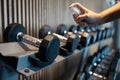 Hand of asian woman is spraying alcohol on the handle of the dumbbell to clean it,prevent Coronavirus infection,safety of the