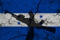 Hand assault rifle on the background of the flag of Honduras and cracks. Honduras Power Concept