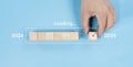 Hand assemble wooden block cube to update technology downloading tool bar status from 2024 to 2025
