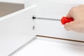 Hand assembling, tighgting details of white furniture using a screwdriver