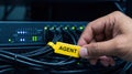 Hand attaching yellow AGENT tag to server cables in data center Concept of network security, IT management, and system Royalty Free Stock Photo