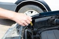 Hand of auto mechanic with a tool checking oil level