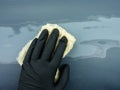 the hand of the auto painter in a black glove holds a special napkin for dusting the surface of the car.