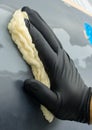 the hand of the auto-painter in a black glove holds a special napkin for dusting the surface of the car.