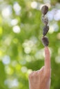 Hand Balance Stones on Finger Blurred Green Bkgrnd