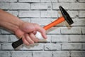 Hand with bandaged finger holds hammer on brick wall background. Accident at work. hand of builder with an injured finger Royalty Free Stock Photo