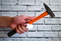 Hand with bandaged finger holds hammer on brick wall background. Accident at work. hand of builder with an injured finger Royalty Free Stock Photo