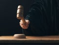 Hand banging gavel on dark background, the judge makes a verdict,