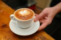 Hand barista holding and serving cup of coffee.