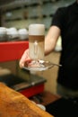 Hand barista holding and serving glass of latte