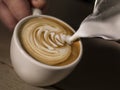 Hand of barista making cappuccino coffee pouring milk making lat