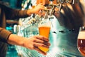 Hand of bartender pouring a large lager beer in tap.